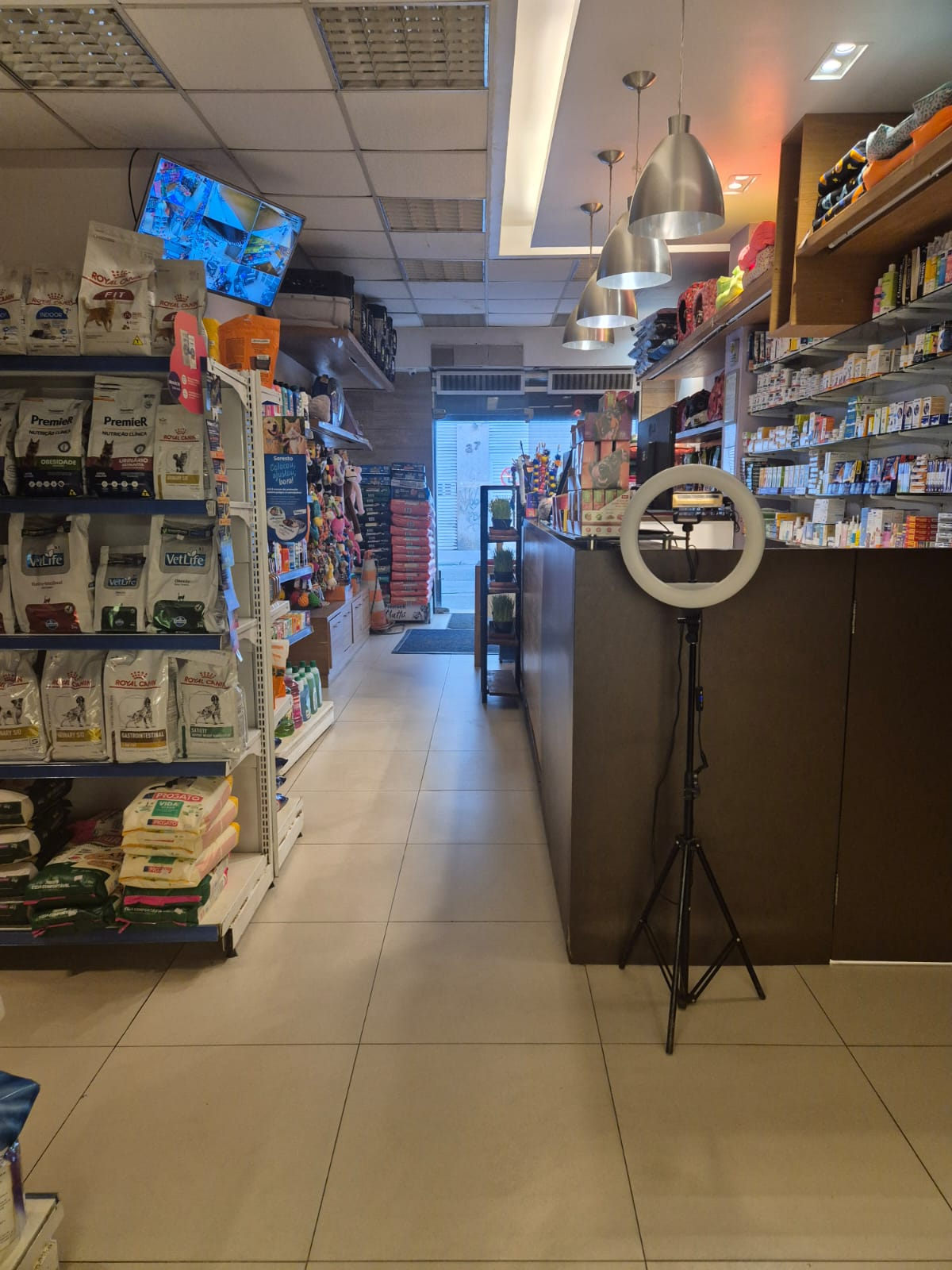 Vista interna da loja com corredor de rações, balcão de atendimento e prateleiras de produtos